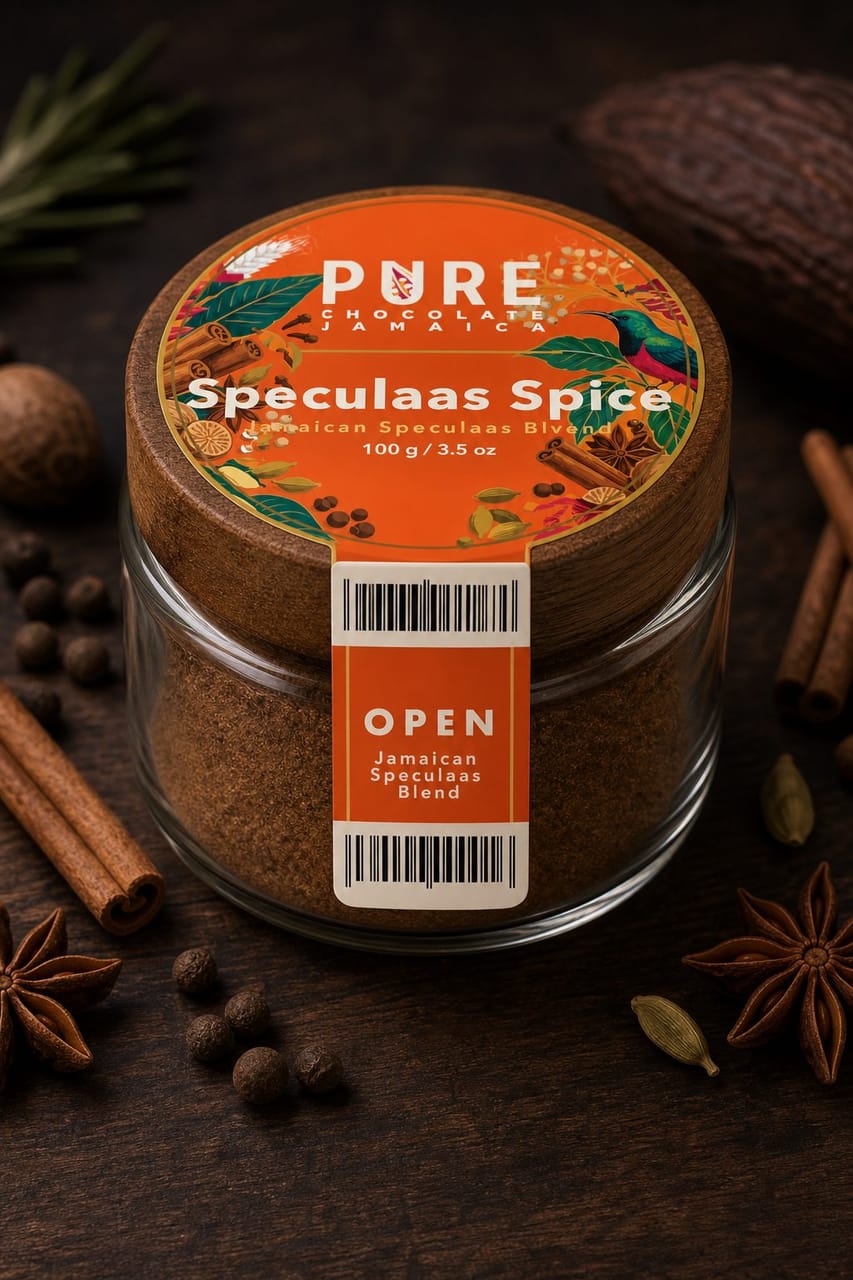 Speculaas Spice jar from above — a wooden-lidded glass jar with an orange circular lid label, ringed by cinnamon, star anise, nutmeg and cardamom.